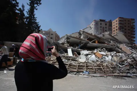 A Palestinian woman takes a picture for the rubble of a residential tower, which witnesses said was destroyed in an Israeli air strike, in Gaza City August 24, 2014. Egypt called on Israel and the Palestinians on Saturda...