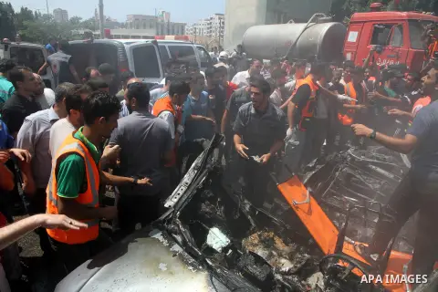 Palestinians gather around the remains of a car, which witnesses said was hit by an Israeli air strike, in Gaza City August 24, 2014. Israel launched more air strikes on Gaza on Sunday after taking its military campaign...