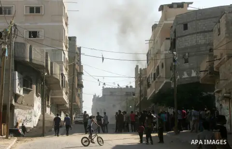 Palestinians run to take cover after an Israeli strike hits a building belonging to the Abu Marouf family in Khan Younis in the southern Gaza Strip, Sunday, Aug. 24, 2014. Photo by Abed Rahim Khatib