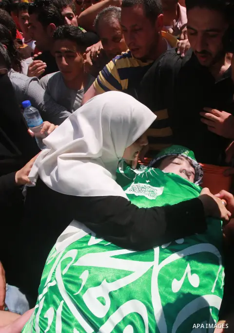 The mother of Hassan Ashour, a Palestinian teenager who died of his injuries, mourns over his body during his funeral on August 25, 2014 in the West Bank city of Nablus. Hassan Ashur was shot in the abdomen with live fir...