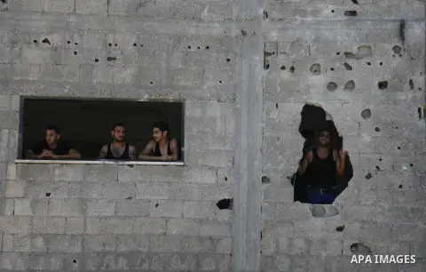 Palestinians look out their house on the rubble of a house targeted in an Israeli air strike in Gaza city on August 25, 2014. Israel's Prime Minister Benjamin Netanyahu warned Palestinian civilians on Sunday to leave imm...