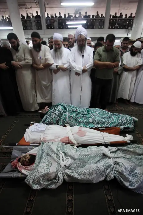 Palestinians mourn over the bodies of Basim Hijazi 36, his brother Ahmed, 26, and a friend Mohamad al-Dali who were killed when their car was hit by an Israeli air strike during their funeral in Gaza City on August 25, 2...