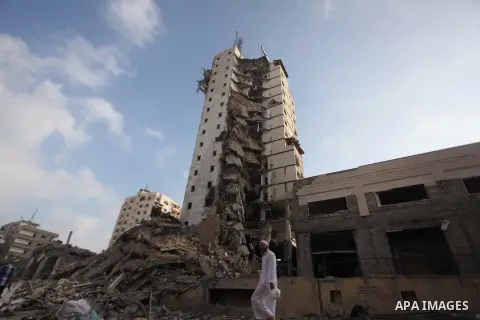 A Palestinian man walks past the remains of one of Gaza's tallest apartment towers, which witnesses said was hit by an Israeli air strike that destroyed much of it, in Gaza City August 26, 2014. Israeli air strikes launc...