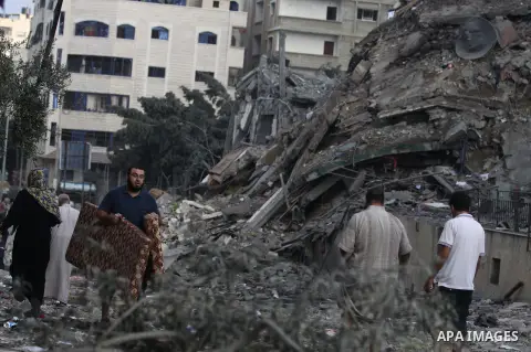 Palestinians collect their belongings from under the rubble of one of Gaza's tallest apartment towers, which witnesses said was hit by an Israeli air strike that destroyed much of it, in Gaza City August 26, 2014. Israel...