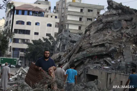 Palestinians collect their belongings from under the rubble of one of Gaza's tallest apartment towers, which witnesses said was hit by an Israeli air strike that destroyed much of it, in Gaza City August 26, 2014. Israel...
