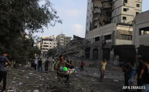 Palestinians collect their belongings from under the rubble of one of Gaza's tallest apartment towers, which witnesses said was hit by an Israeli air strike that destroyed much of it, in Gaza City August 26, 2014. Israel...