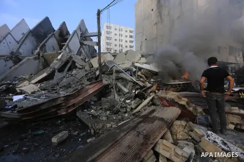 Fire is seen as a Palestinian man walks amidst the remains of a tower building housing offices, which witnesses said was destroyed by an Israeli air strike, in Gaza City August 26, 2014. Israeli air strikes launched befo...