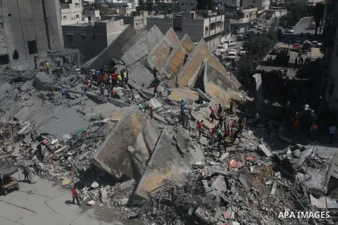 Palestinians gather around the remains of a tower building housing offices which witnesses said was destroyed by an Israeli air strike in Gaza City August 26, 2014. Israeli air strikes launched before dawn on Tuesday kil...