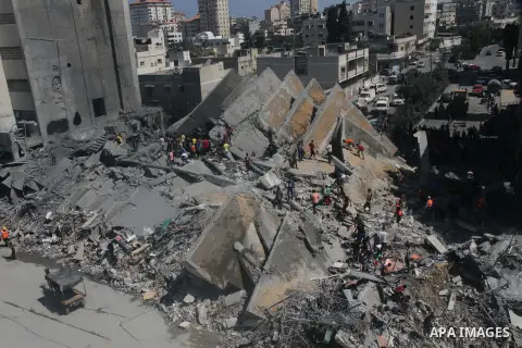 Palestinians gather around the remains of a tower building housing offices which witnesses said was destroyed by an Israeli air strike in Gaza City August 26, 2014. Israeli air strikes launched before dawn on Tuesday kil...