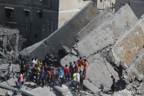 Palestinians gather around the remains of a tower building housing offices which witnesses said was destroyed by an Israeli air strike in Gaza City August 26, 2014. Israeli air strikes launched before dawn on Tuesday kil...