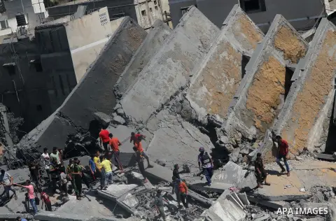 Palestinians gather around the remains of a tower building housing offices which witnesses said was destroyed by an Israeli air strike in Gaza City August 26, 2014. Israeli air strikes launched before dawn on Tuesday kil...