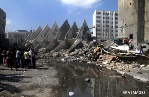 Palestinians gather around the remains of a tower building housing offices which witnesses said was destroyed by an Israeli air strike in Gaza City August 26, 2014. Israeli air strikes launched before dawn on Tuesday kil...