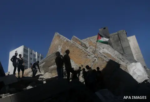 Palestinians gather around the remains of a tower building housing offices which witnesses said was destroyed by an Israeli air strike in Gaza City August 26, 2014. Israeli air strikes launched before dawn on Tuesday kil...