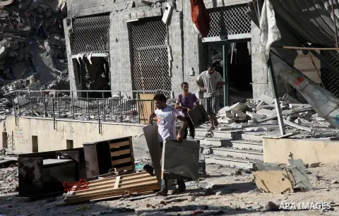 Palestinians collect their belongings from under the rubble of one of Gaza's tallest apartment towers, which witnesses said was hit by an Israeli air strike that destroyed much of it, in Gaza City August 27, 2014. The op...