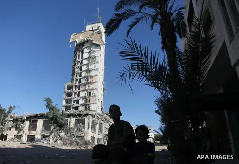 Palestinian boy sits in front of Gaza's tallest apartment towers, which witnesses said was hit by an Israeli air strike that destroyed much of it, in Gaza City August 27, 2014. The open-ended ceasefire in the Gaza war be...