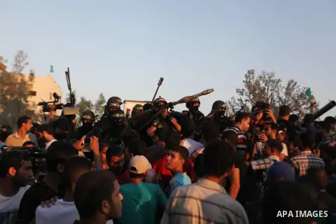 Palestinian militants of Izzedine al-Qassam Brigades, military wing of Hamas, and their supporters celebrate a victory rally at the debris of destroyed houses in Shijaiyah, neighborhood of Gaza City, in the northern Gaza...