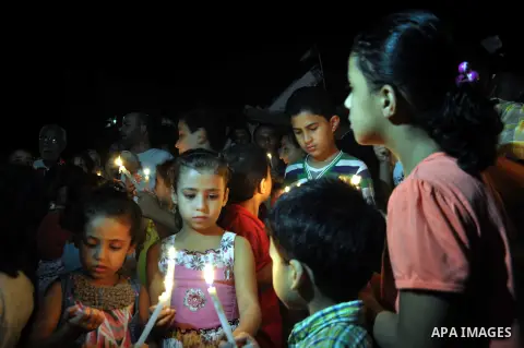 Palestinian Families hold candles during a protest in front of the remains El Zafer Tower destroyed in an israeli airstrike, in Gaza city, on Aug. 27, 2014. The open-ended ceasefire in the Gaza war between Israel and the...
