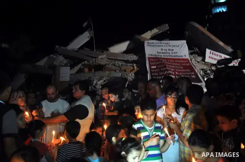 Palestinian Families hold candles during a protest in front of the remains El Zafer Tower destroyed in an israeli airstrike, in Gaza city, on Aug. 27, 2014. The open-ended ceasefire in the Gaza war between Israel and the...
