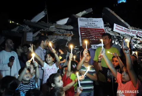 Palestinian Families hold candles during a protest in front of the remains El Zafer Tower destroyed in an israeli airstrike, in Gaza city, on Aug. 27, 2014. The open-ended ceasefire in the Gaza war between Israel and the...