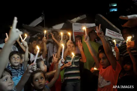 Palestinian Families hold candles during a protest in front of the remains El Zafer Tower destroyed in an israeli airstrike, in Gaza city, on Aug. 27, 2014. The open-ended ceasefire in the Gaza war between Israel and the...