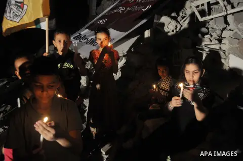 Palestinian Families hold candles during a protest in front of the remains El Zafer Tower destroyed in an israeli airstrike, in Gaza city, on Aug. 27, 2014. The open-ended ceasefire in the Gaza war between Israel and the...