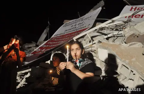 Palestinian Families hold candles during a protest in front of the remains El Zafer Tower destroyed in an israeli airstrike, in Gaza city, on Aug. 27, 2014. The open-ended ceasefire in the Gaza war between Israel and the...