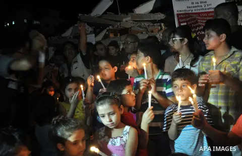 Palestinian Families hold candles during a protest in front of the remains El Zafer Tower destroyed in an israeli airstrike, in Gaza city, on Aug. 27, 2014. The open-ended ceasefire in the Gaza war between Israel and the...