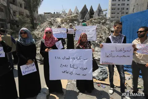 Palestinian women hold banners as they take part a protest in front of the El-Basha Tower destroyed by Israeli airstrike in Gaza city on August 28, 2014. Israel and Palestinians both boasted of victory in the Gaza war bu...