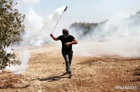 A Palestinian demonstrator throws a gas cannister using a sling shot during clashes with Israeli security personnel in the village of Bilin, near the West Bank city of Ramallah after a march in support the resistance in...