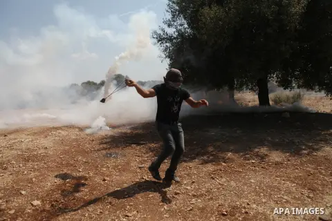 A Palestinian demonstrator throws a gas cannister using a sling shot during clashes with Israeli security personnel in the village of Bilin, near the West Bank city of Ramallah after a march in support the resistance in...