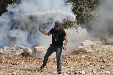 A Palestinian demonstrator throws a gas cannister using a sling shot during clashes with Israeli security personnel in the village of Bilin, near the West Bank city of Ramallah after a march in support the resistance in...
