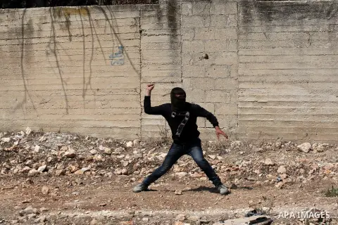 Palestinian protester hurls stones at Israeli soldiers during weekly clashes over the Jewish settlement of Qadomem at Kofr Qadom village, near West Bank city of Nablus, 29 August 2014. Photo by Nedal Eshtayah