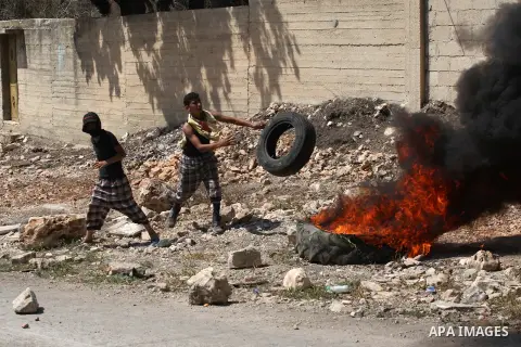 A Palestinian protester carries tyres during weekly clashes over the Jewish settlement of Qadomem at Kofr Qadom village, near West Bank city of Nablus, 29 August 2014. Photo by Nedal Eshtayah