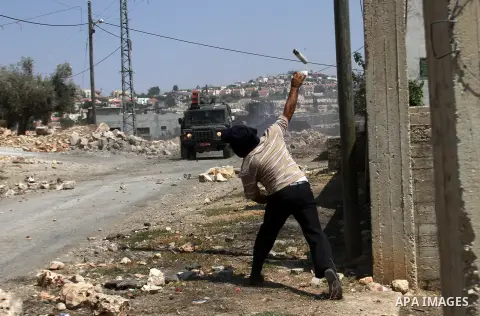 Palestinian protester hurls stones at Israeli soldiers during weekly clashes over the Jewish settlement of Qadomem at Kofr Qadom village, near West Bank city of Nablus, 29 August 2014. Photo by Nedal Eshtayah