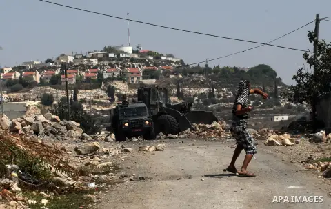 Palestinian protester hurls stones at Israeli soldiers during weekly clashes over the Jewish settlement of Qadomem at Kofr Qadom village, near West Bank city of Nablus, 29 August 2014. Photo by Nedal Eshtayah