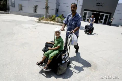 A Palestinian father wheels his wounded son as they wait to be given the permission to cross into Egypt at the Rafah border crossing in the southern Gaza Strip, on August 28, 2014. The Rafah crossing with Egypt is Gaza's...