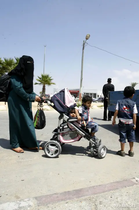 A Palestinian mother wheels his son as they wait to be given the permission to cross into Egypt at the Rafah border crossing in the southern Gaza Strip, on August 28, 2014. The Rafah crossing with Egypt is Gaza's only ga...