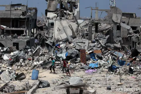 Palestinians walk past buildings destroyed during fighting between Hamas militants and Israel in the Al-Shaaf neighbourhood, in Gaza City, on August 31, 2014. An indefinite ceasefire to end seven weeks of fighting betwee...