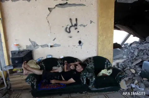 Palestinians sit on a sofa at their house which destroyed during fighting between Hamas militants and Israel in the Al-Shaaf neighbourhood, in Gaza City, on August 31, 2014. An indefinite ceasefire to end seven weeks of...