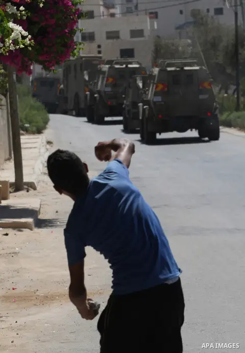 A Palestinian youth throws at Israeli military patrols during a military operation at Ein Beit Alma' refugee camp near the West Bank city of Nablus, on Sep. 03, 2014. Photo by Nedal Eshtayah