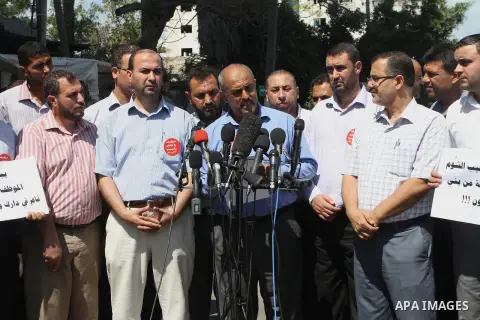 Former head of the union staff in Gaza, Mohammed Siam speaks during a press conference as Palestinian employees of the former government in Gaza Strip hold placards during a protest against not receiving their salaries,...