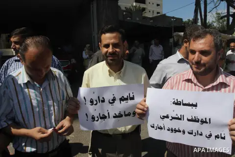 Palestinian employees of the former government in Gaza Strip hold placards during a protest against not receiving their salaries, outside a Bank in Gaza City Sep. 07, 2014. Many issues involving the Strip, such as the fa...