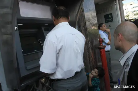 Palestinian employees paid by the Palestinian Authority wait to receive their salaries from an ATM, outside a Bank in Gaza City Sep. 07, 2014. Many issues involving the Strip, such as the fate of former employees of the...