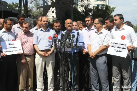 Former head of the union staff in Gaza, Mohammed Siam speaks during a press conference as Palestinian employees of the former government in Gaza Strip hold placards during a protest against not receiving their salaries,...