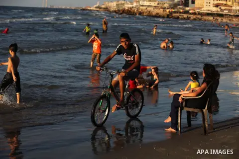 A Palestinian boy ride a bicycle on the beach in Gaza city, on Sep. 07, 2014. Photo by Ashraf Amra