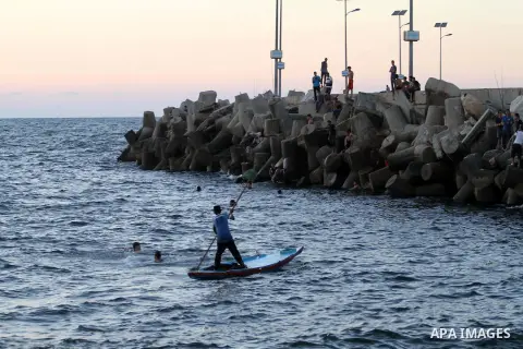 A Palestinian man rides his boat at Gaza's seaport in Gaza City at sunset on on Sept. 9, 2014. The Israeli navy arrested four Palestinian fishermen and seized their boat a Gaza official says, in one of the first instance...