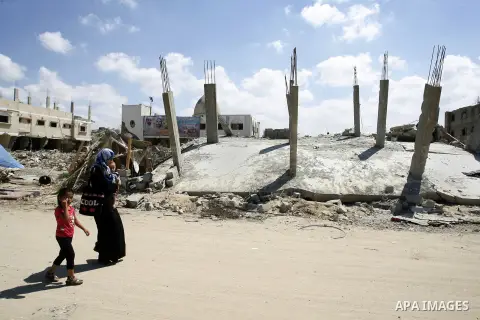 A Palestinian woman with her kids walk past a destroyed house in Khan Yunis in the southern Gaza Strip on September 11, 2014. Israel's deputy foreign minister,Tzahi Hanegbi , warned that Hamas was likely to resume "viole...