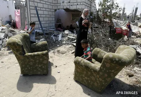 A Palestinian woman works as her sons play at their destroyed house in Khan Yunis in the southern Gaza Strip on September 11, 2014. Israel's deputy foreign minister,Tzahi Hanegbi , warned that Hamas was likely to resume...