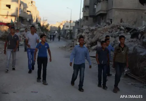 Palestinian students walk past houses that witnesses said were destroyed by the Israeli offensive, as they make their way to school on the first day of the new school year in the east of Gaza City September 14, 2014. An...