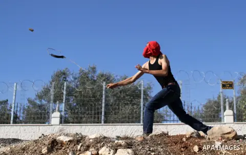 A Palestinian protester throws stones towards Israeli security forces during clashes at a protest against the Jewish settlement of Ofra, in the West Bank village of Silwad, near Ramallah September 19, 2014 . Photo by Sha...